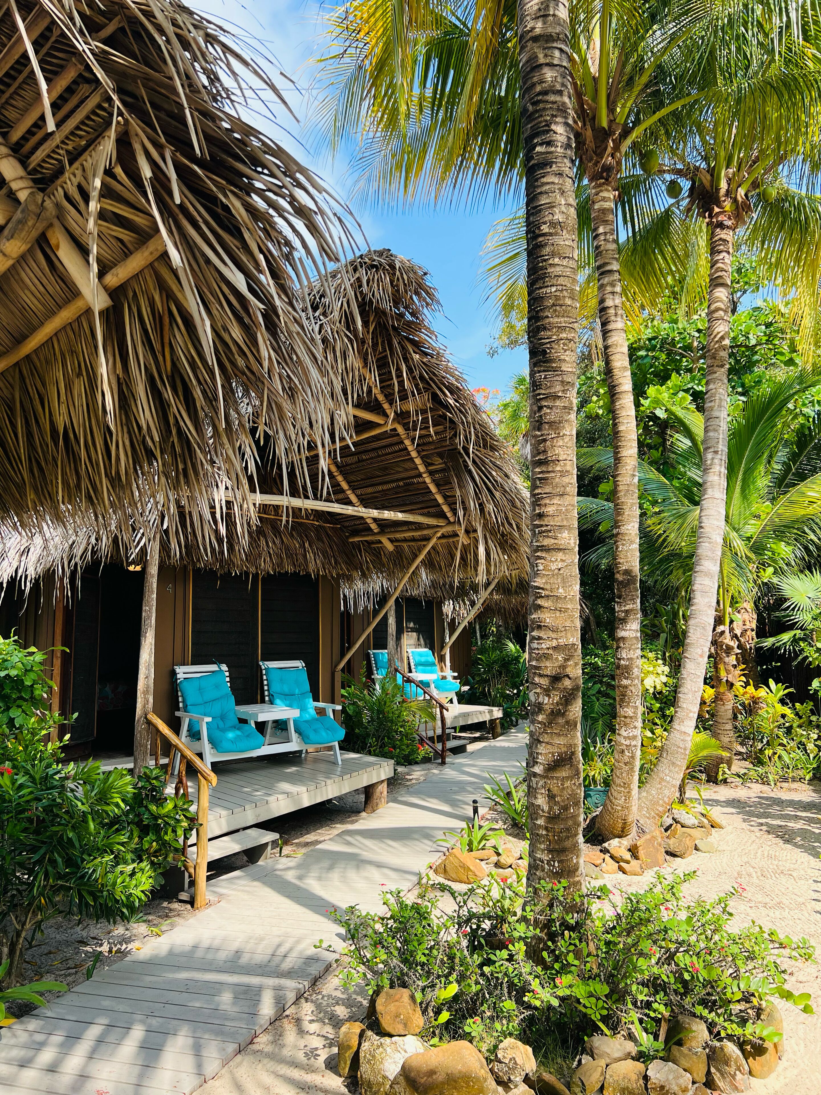 A thatched-roof structure with outdoor seating and palm trees.