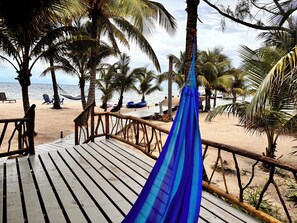 A wooden deck with a hammock, palm trees, and beach chairs. - Azure Del Mar (Placencia)