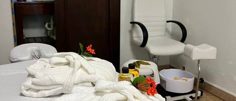 A room with a bed, a white chair, and a wooden door.