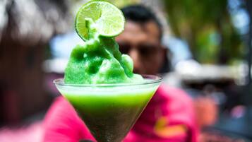 Un cóctel verde en una copa de martini, adornado con una rodaja de lima.