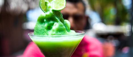 Un cocktail vert servi dans un verre à martini, décoré d’une tranche de citron vert.