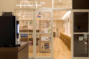 A library cafe with a coffee machine, bookshelves, and seating areas. - Comfort Hotel Miyazaki (Miyazaki)