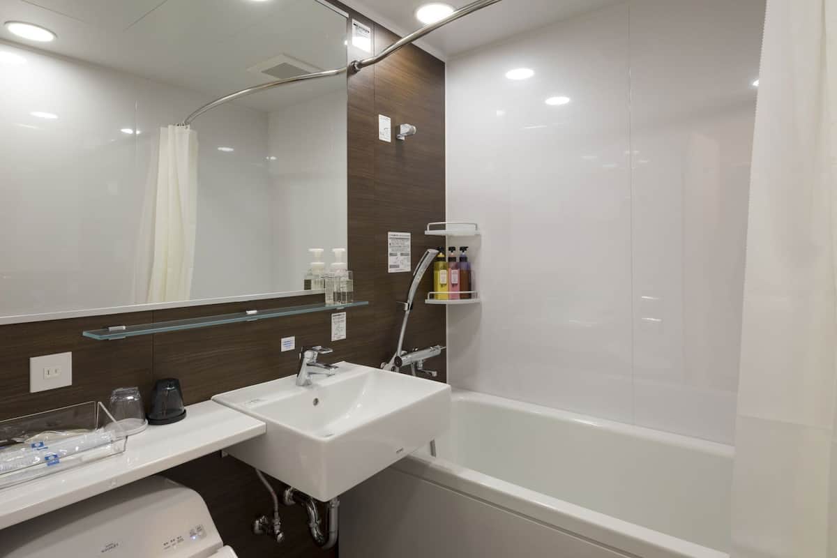 A modern bathroom with a white sink, mirror, and shower.