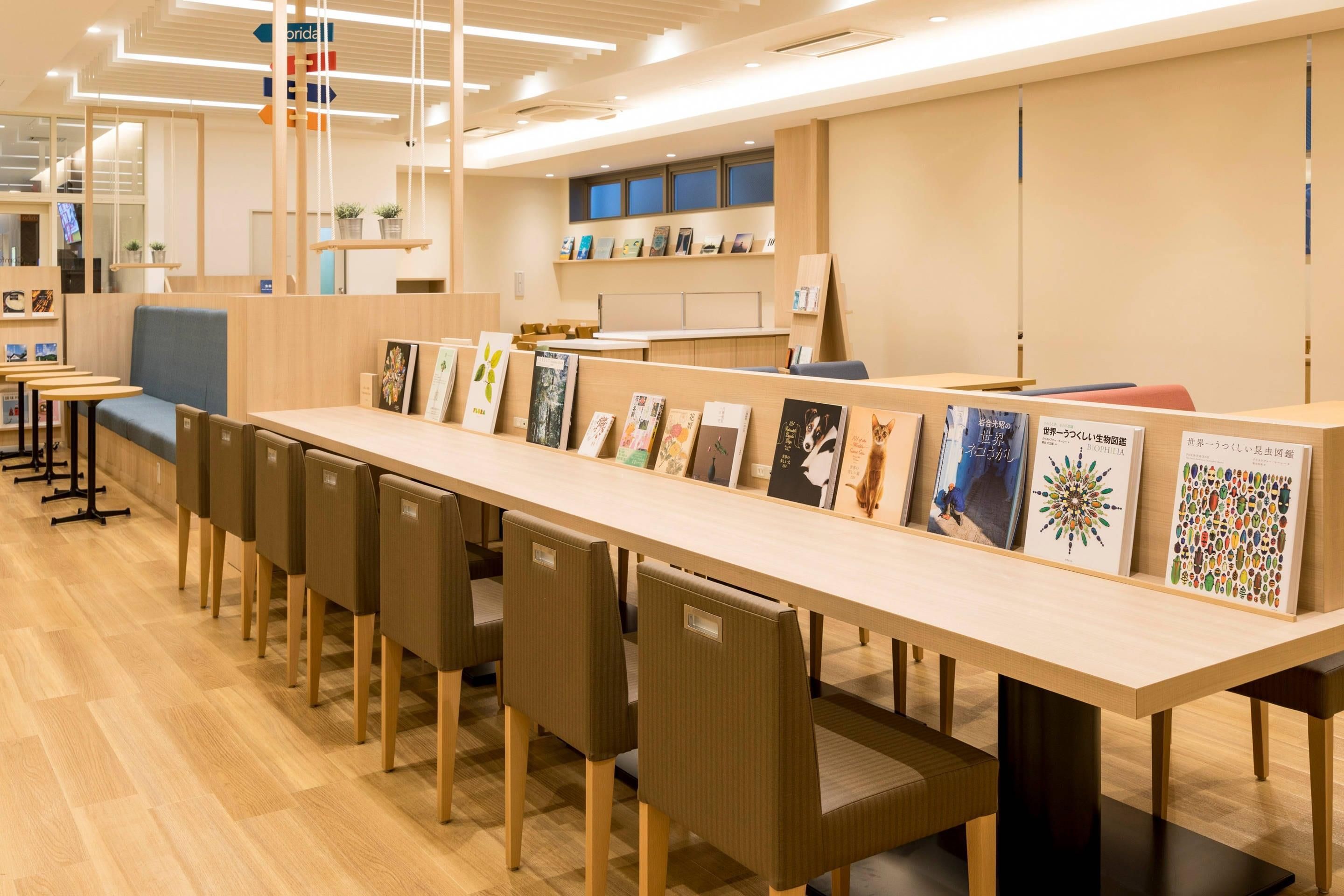 Una habitación moderna y luminosa con una mesa larga que exhibe diversas obras de arte enmarcadas, asientos cómodos y un diseño limpio y minimalista.