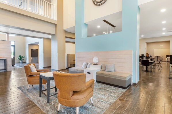 A spacious living area with a high ceiling, a sofa set, a coffee table, and a dining area with chairs. - Caretta Landing Sarasota, an Ascend Collection Hotel (Sarasota)