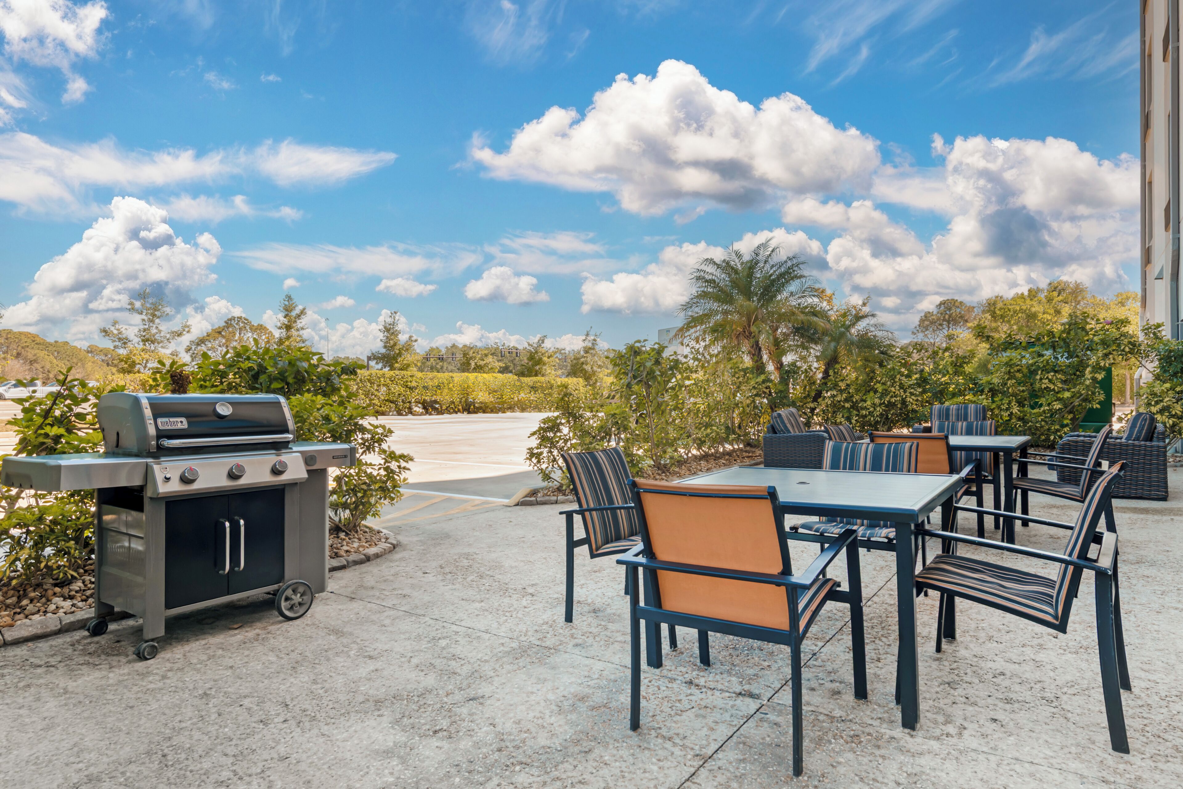 An outdoor patio with a grill, seating area, and a view of the sky.
