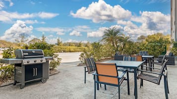 An outdoor patio with a grill, seating area, and a view of the sky.