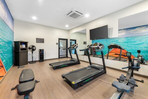 A fitness center with treadmills, a rowing machine, and a wall mural of a boat on water. - Caretta Landing Sarasota, an Ascend Collection Hotel (Sarasota)