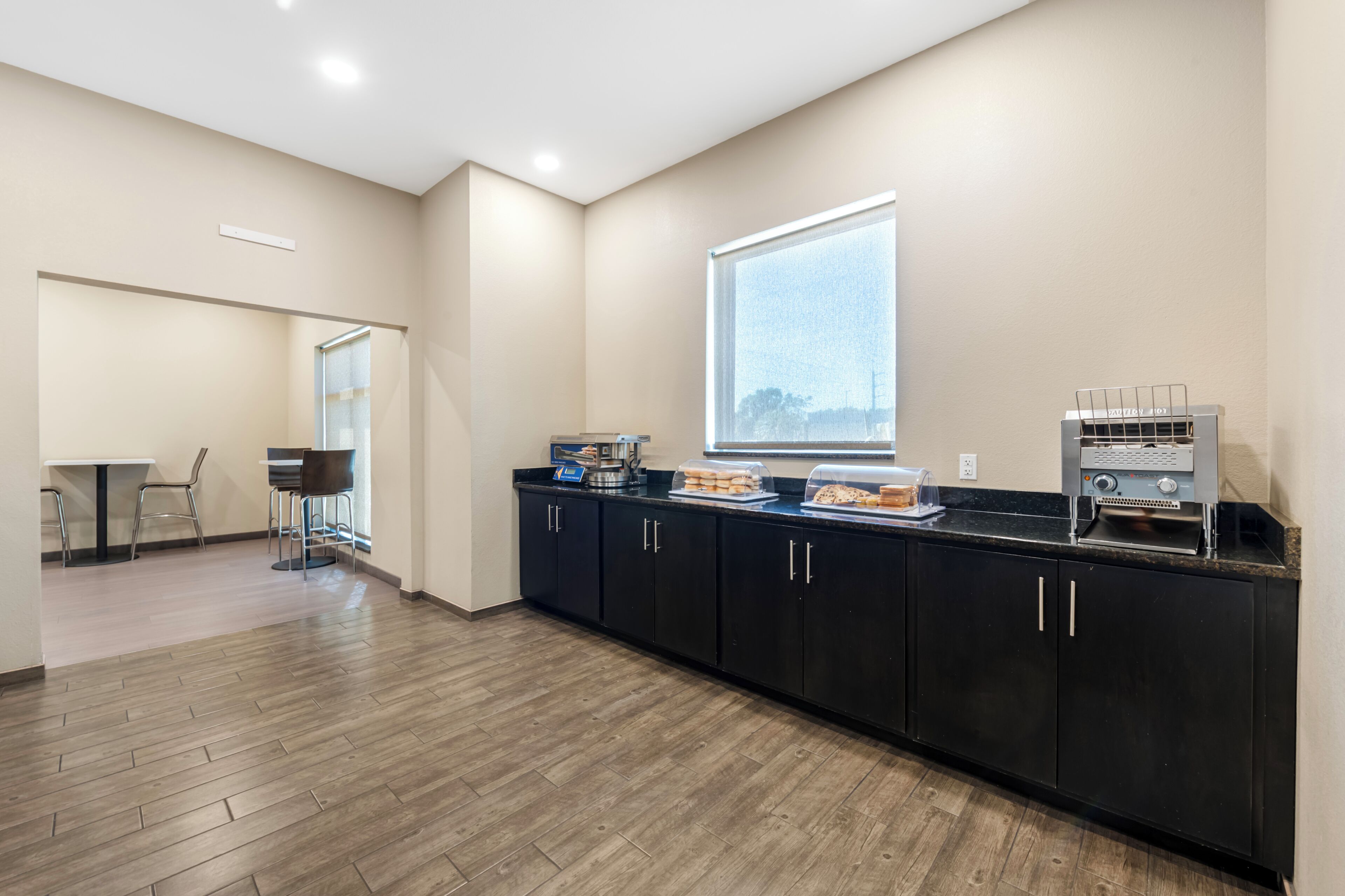 A modern kitchen with a breakfast bar, black cabinets, and a window.