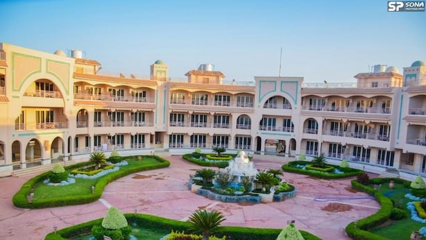 A hotel courtyard with a central fountain, surrounded by manicured gardens and multiple-story buildings with balconies.