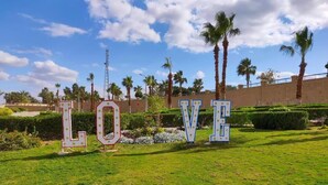Large letters spelling "LOVE" in a garden with palm trees and a clear sky.