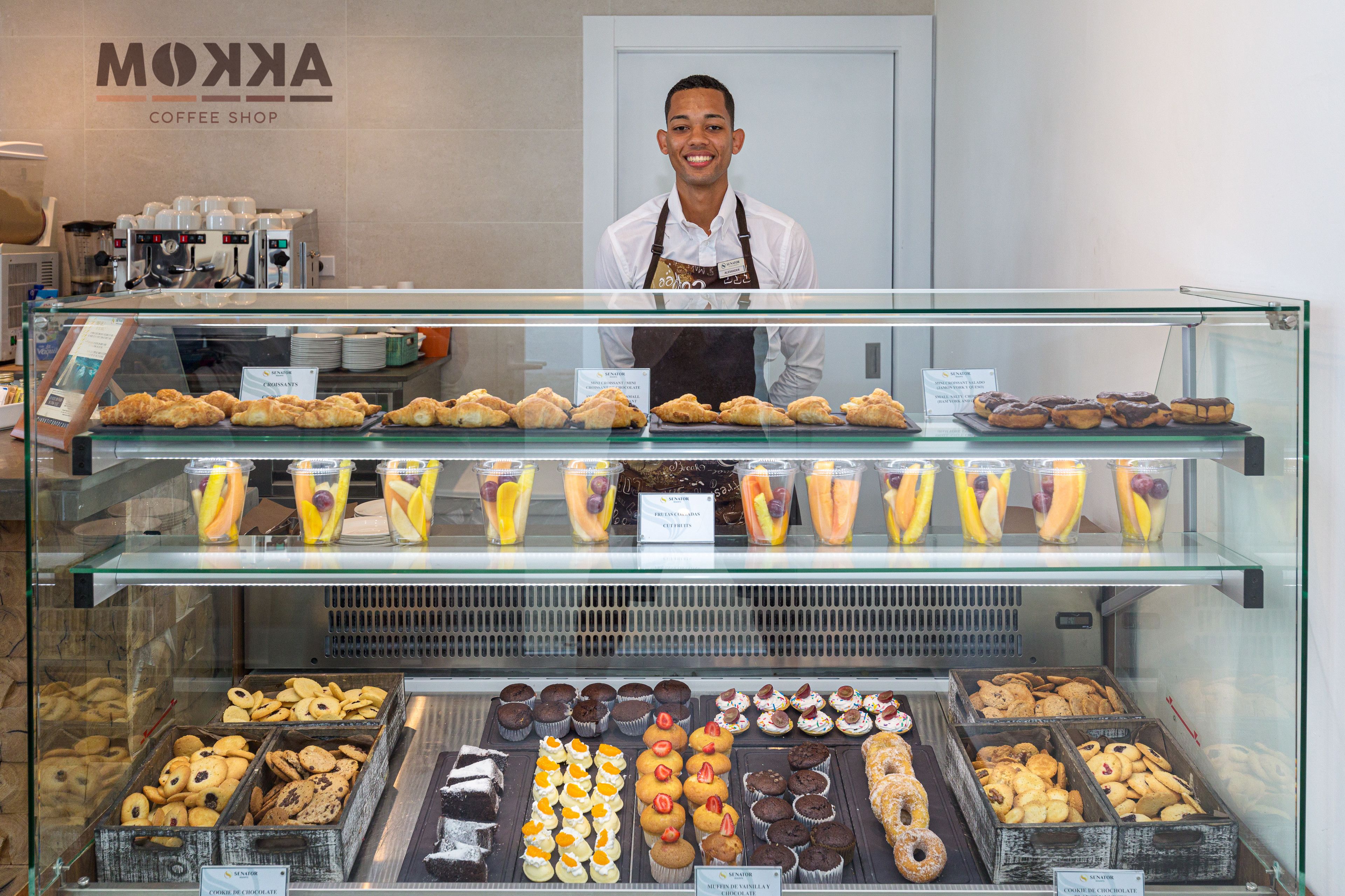 Una vitrina de pastelería con diferentes productos horneados y un letrero de cafetería al fondo.