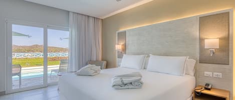 A hotel room with a large bed, a ceiling fan, a nightstand, and a view of a pool and landscape through the sliding glass door.