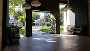 A spacious lobby with a modern design, featuring a large open area with a view of the outside, a seating area with a sofa and chairs, and hanging pendant lights. - Senator Puerto Plata - All inclusive (Puerto Plata)