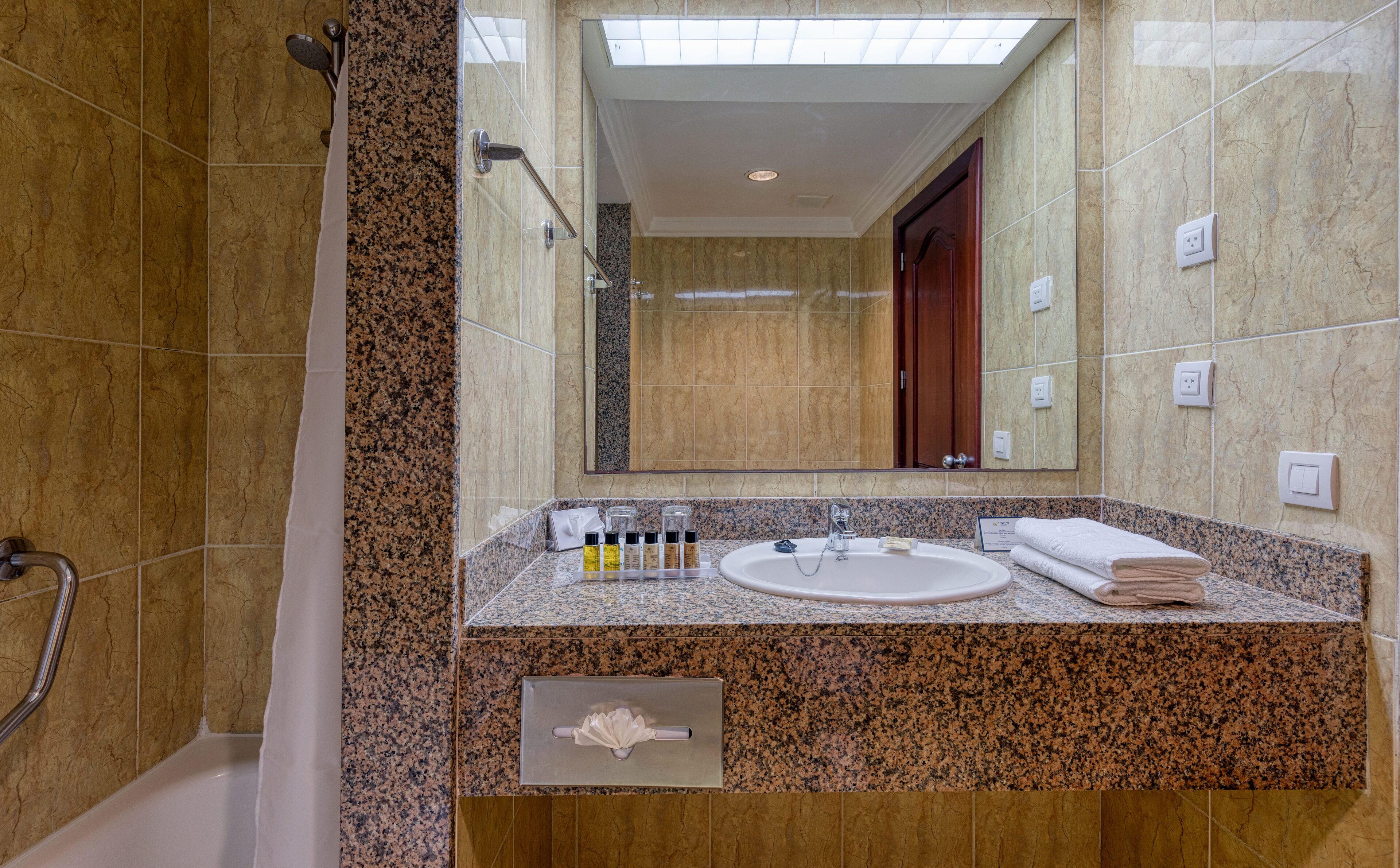 Ein Badezimmer mit Granitplatte, Waschbecken und Spiegel.