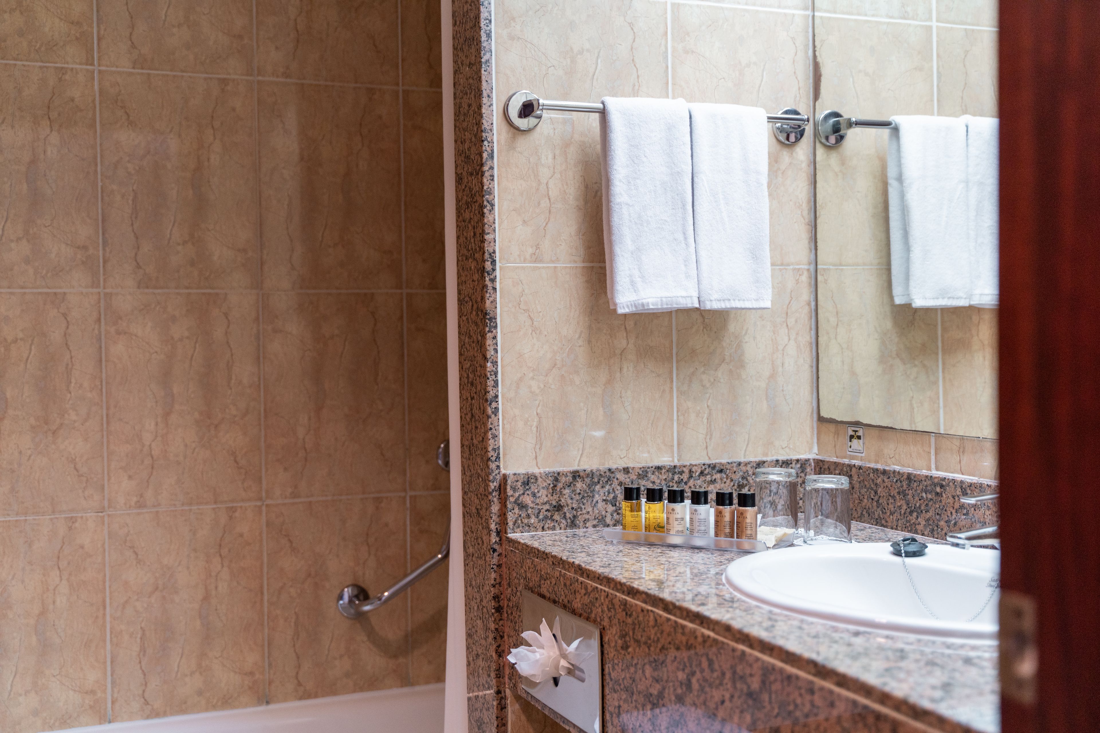 A bathroom with a granite countertop, a sink, and a mirror. There are two towels hanging on a towel rack.