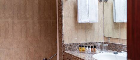 A bathroom with a granite countertop, a sink, and a mirror. There are two towels hanging on a towel rack.