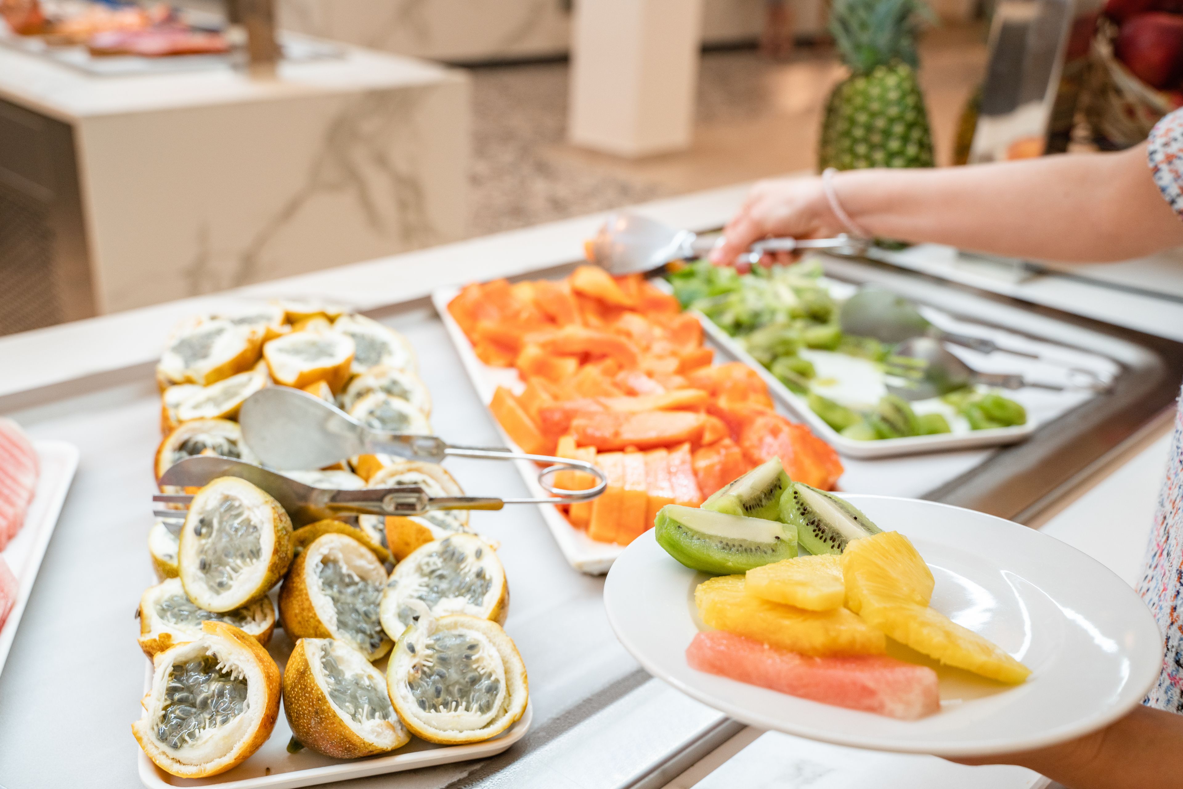 A buffet with various fruits and vegetables, including sliced kiwi, pineapple, and watermelon.