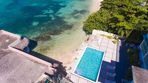 An aerial view of a resort with a clear blue pool, a sandy beach, and lush greenery. - Ocean Rooms at Oceans Palm Resort (Ocho Rios)