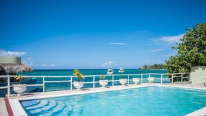 A pool with a view of the ocean and boats. - Ocean Rooms at Oceans Palm Resort (Ocho Rios)
