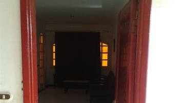 An open wooden door leading to a room with a tiled floor and a bench.