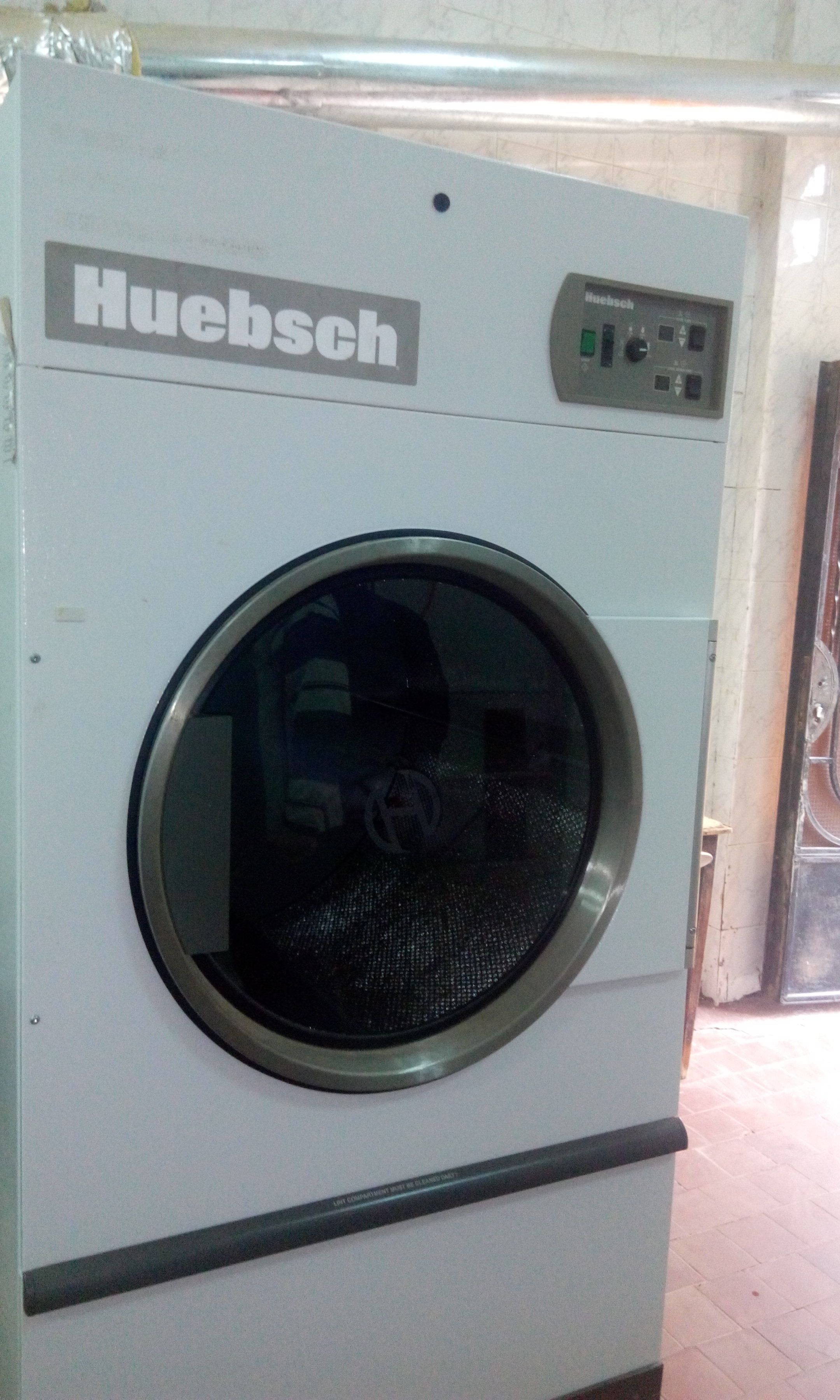 Huebschin etuaukollinen pyykinpesukone, jossa on ohjauspaneeli ja pyöreä luukku.