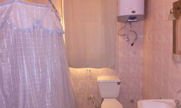 A bathroom with a toilet, a shower, and a sink.