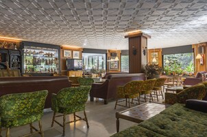 Un vestíbulo amplio con techo estampado, zonas de estar cómodas y un bar con elementos decorativos.