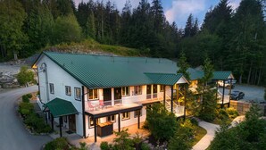 Un chalet à deux étages doté d’un toit végétalisé, d’un porche couvert et d’un mur de soutènement en pierre.