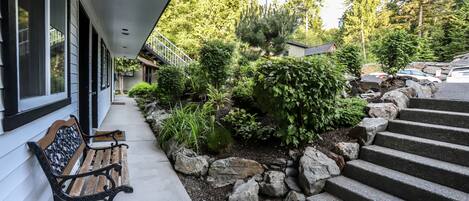 A bench outside a building with a stone pathway and steps leading up to a house.