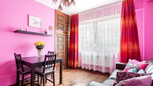 A room with a dining table and chairs, a sofa, a decorative wall panel, and a window with curtains. - Tower Bridge Apartment (London)