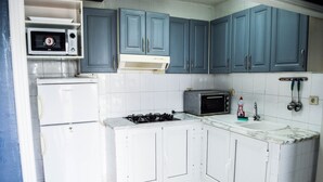 A kitchen with white cabinets, a microwave, a stove, and a sink. - Cosy Apartment in Sidi Bou Said- Amilcar (Sidi Bou Said)
