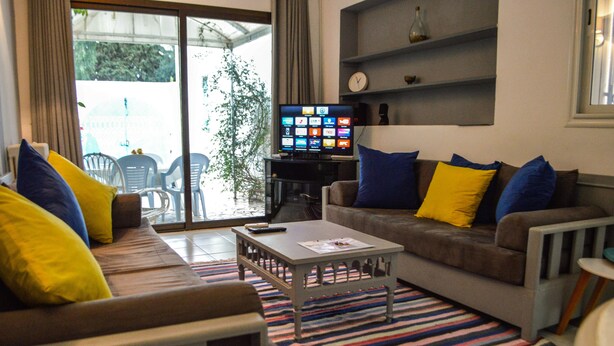 A living room with a sofa, armchairs, a coffee table, and a television. - Cosy Apartment in Sidi Bou Said- Amilcar (Sidi Bou Said)