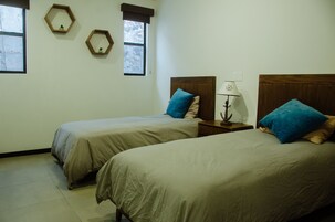 A bedroom with two single beds, a nightstand with a lamp, and two hexagonal mirrors on the wall.