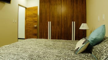 A bedroom with a bed, a wardrobe, and a television mounted on the wall.
