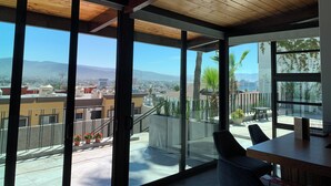 A modern interior with large windows, a wooden ceiling, and a view of a cityscape. - El Refugio (Ensenada)