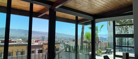 A modern interior with large windows, a wooden ceiling, and a view of a cityscape.