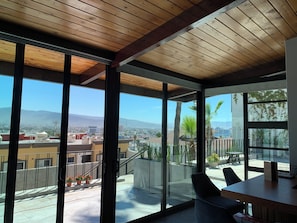 A modern interior with large windows, a wooden ceiling, and a view of a cityscape. - El Refugio (Ensenada)