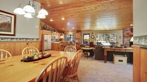 A cozy cabin interior with a wooden dining table, chairs, a kitchen area with wooden cabinets, and a living space with a sofa and a coffee table. - 5 Modoc-Sunriver, Oregon: Hot Tub, BBQ, WiFi, SHARC Aquatics, Tubing Hill, Mt. Bachelor, Golf, Deschutes River, Tennis, Bike Paths (Sunriver)