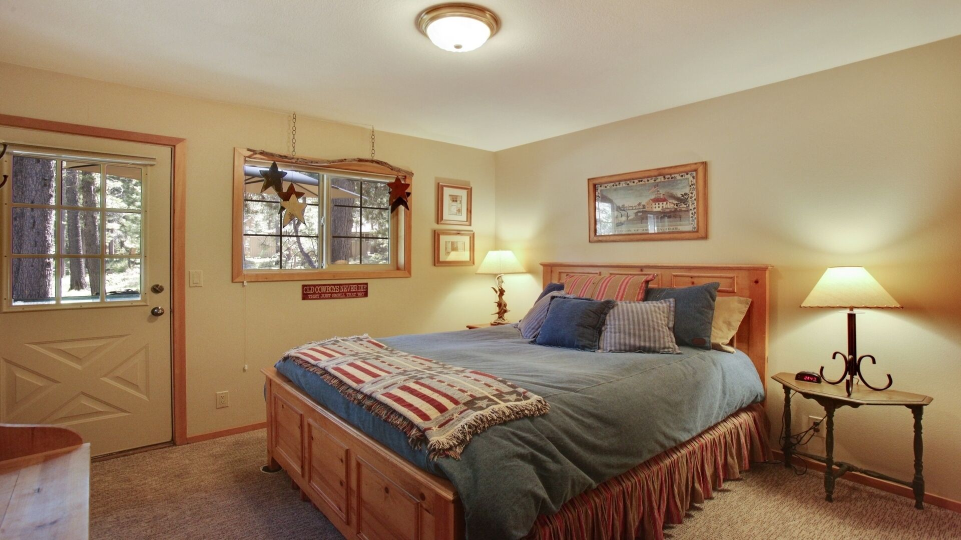 Un dormitorio con una cama, dos mesitas de noche, un ventanal decorado con estrellas y una puerta.