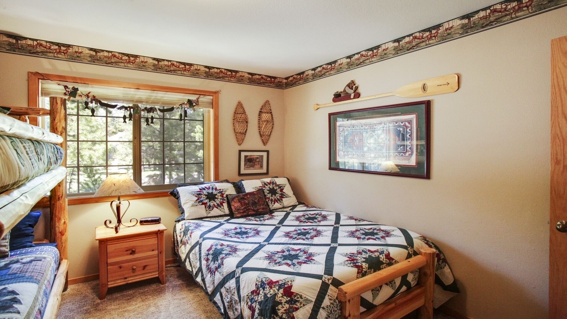 Un dormitori acollidor amb un llit de fusta, una tauleta de nit, una finestra amb cortines i una paret decorada amb un quadre i penjolls.
