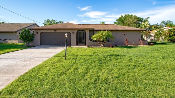 A single-story house with a front garage, a well-maintained lawn, and a clear sky. - Villa Florida Flair - a Quiet Family Paradise in the Heart of Cape Coral (Cape Coral)