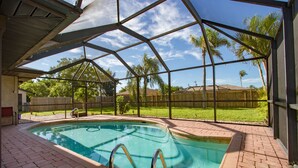 A covered swimming pool with a clear view of the surrounding area, including a wooden fence and palm trees. - Villa Florida Flair - a Quiet Family Paradise in the Heart of Cape Coral (Cape Coral)
