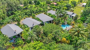 Vue aérienne d’un complexe hôtelier comprenant plusieurs bâtiments, une piscine et une végétation tropicale luxuriante.