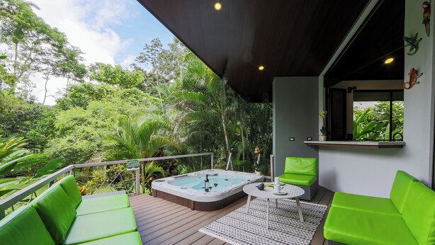 Een hottub op een houten terras, met groene zitplaatsen en een kleine tafel.
