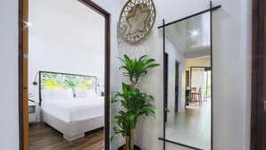 Een moderne slaapkamer met een bed, een grote spiegel en een potplant.