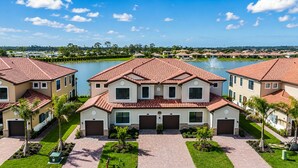 A residential complex with multiple houses, a central courtyard, and a body of water in the background.