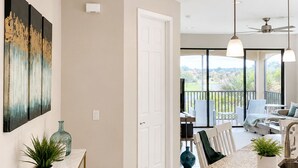 A modern kitchen with a marble countertop, pendant lighting, and a view to an outdoor balcony.