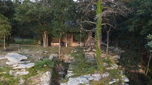 Uma construção rústica de pedra rodeada por folhagem e árvores densas.