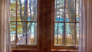 Two windows with a view of trees and a deck. - Vacation at "The Boat House", Private Beach, Near Harbor Springs (Harbor Springs)